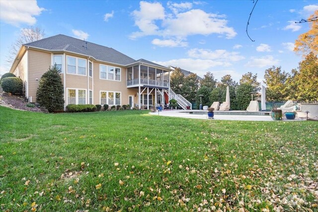 rear view of house with a yard, a patio, and a sunroom