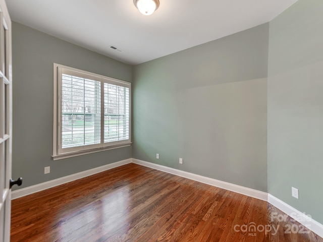 spare room featuring wood finished floors, baseboards, and visible vents