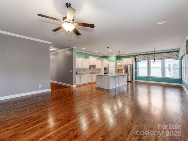 unfurnished living room with baseboards, a ceiling fan, crown molding, a sink, and dark wood-type flooring