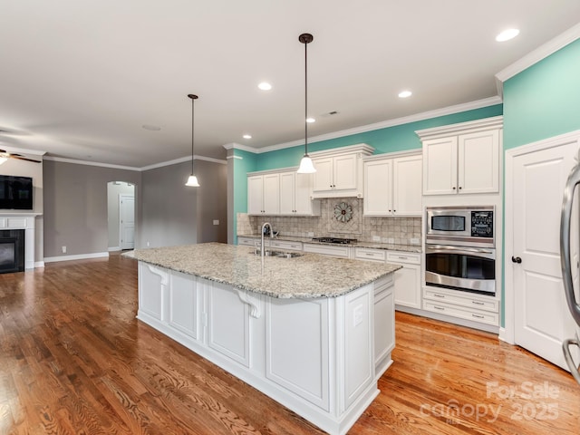 kitchen featuring appliances with stainless steel finishes, white cabinets, decorative light fixtures, and open floor plan