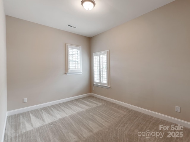 empty room with light colored carpet, baseboards, and visible vents