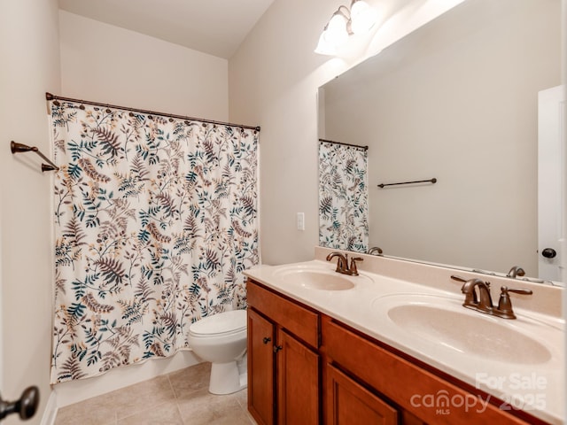 bathroom with tile patterned floors, double vanity, a sink, and toilet