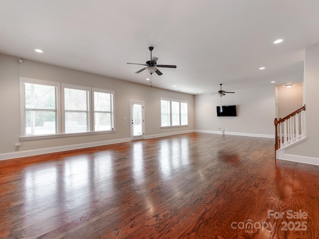 unfurnished living room featuring dark wood-type flooring, recessed lighting, baseboards, and stairway