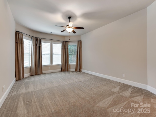 unfurnished room with light carpet, visible vents, a ceiling fan, and baseboards