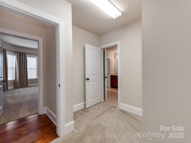 hallway featuring baseboards and light colored carpet