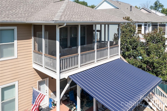 view of side of property featuring roof with shingles and a patio