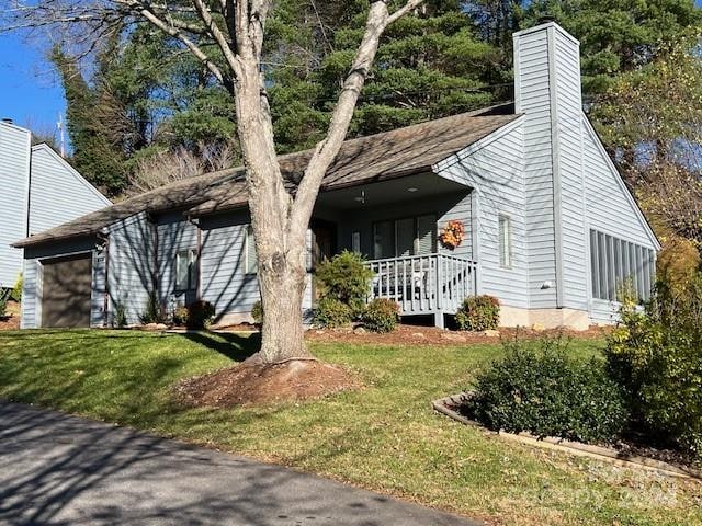 view of front of house with a porch, a garage, and a front lawn