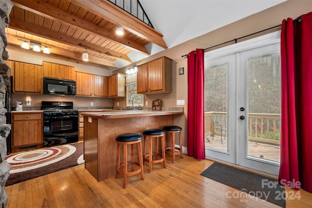 kitchen with a breakfast bar, french doors, black appliances, light hardwood / wood-style flooring, and kitchen peninsula