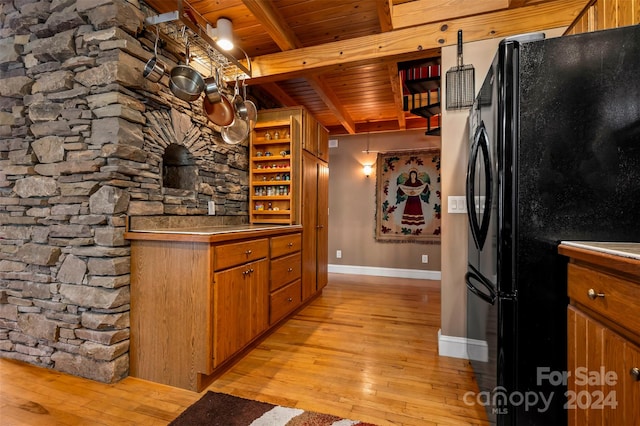 kitchen with beamed ceiling, light hardwood / wood-style floors, black fridge, and wooden ceiling