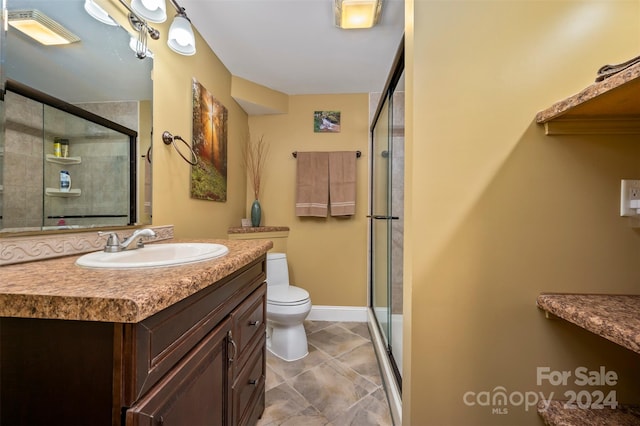 bathroom with a shower with door, vanity, and toilet