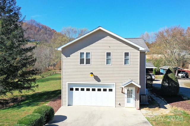 view of home's exterior with a lawn, cooling unit, and a garage