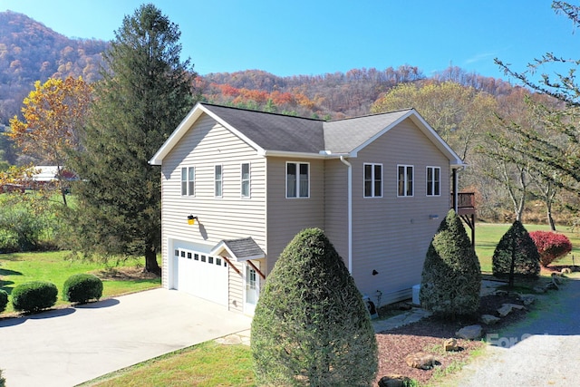 view of side of home featuring a mountain view, a yard, and a garage