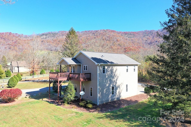 view of side of property featuring a deck with mountain view and a yard