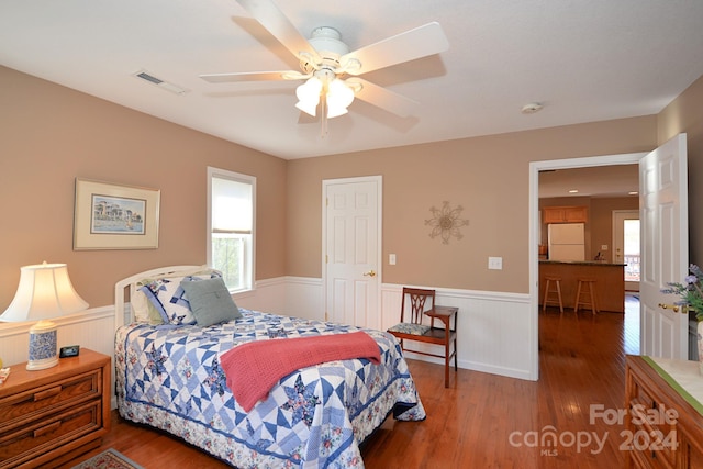 bedroom featuring dark hardwood / wood-style flooring, white fridge, and ceiling fan