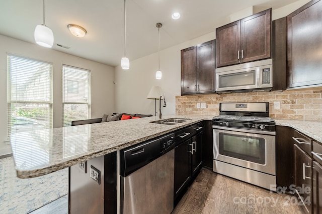 kitchen featuring dark wood-type flooring, sink, appliances with stainless steel finishes, decorative light fixtures, and kitchen peninsula