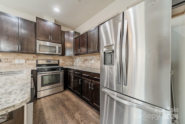 kitchen with light stone countertops, appliances with stainless steel finishes, dark hardwood / wood-style flooring, and sink