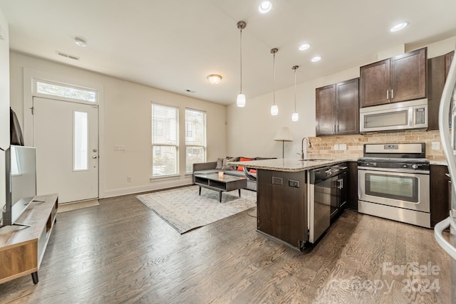 kitchen with sink, hanging light fixtures, light stone counters, dark hardwood / wood-style flooring, and appliances with stainless steel finishes