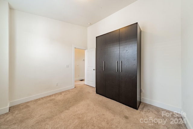 unfurnished bedroom featuring light carpet and a closet