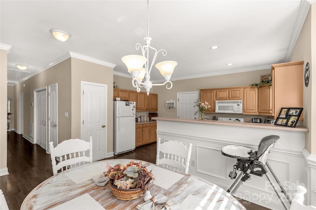 dining area with dark hardwood / wood-style flooring, ornamental molding, and an inviting chandelier