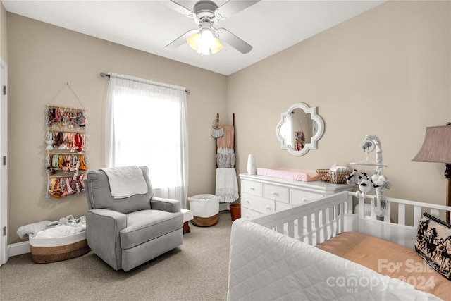 bedroom with a crib, carpet, and ceiling fan