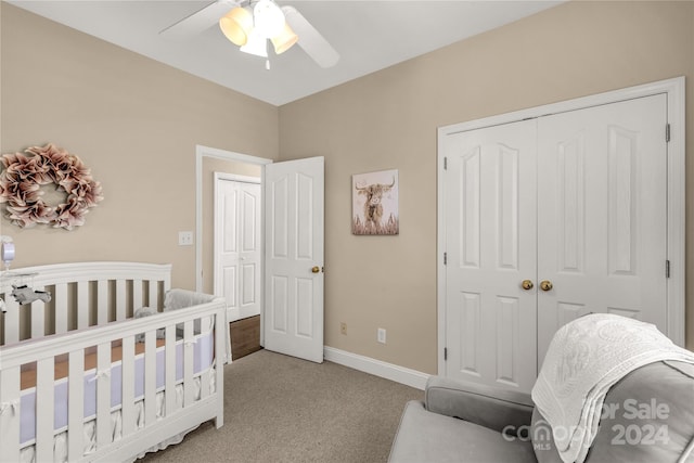 bedroom with light carpet, a nursery area, a closet, and ceiling fan