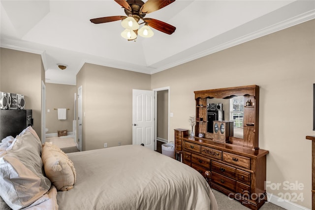 carpeted bedroom with ensuite bathroom, ceiling fan, a raised ceiling, and crown molding