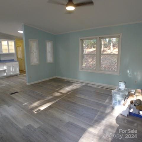 unfurnished living room featuring hardwood / wood-style flooring, ceiling fan, ornamental molding, and vaulted ceiling