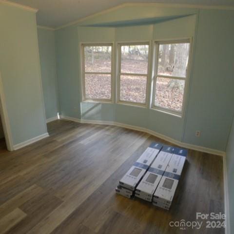 unfurnished room featuring dark hardwood / wood-style floors, ornamental molding, and vaulted ceiling