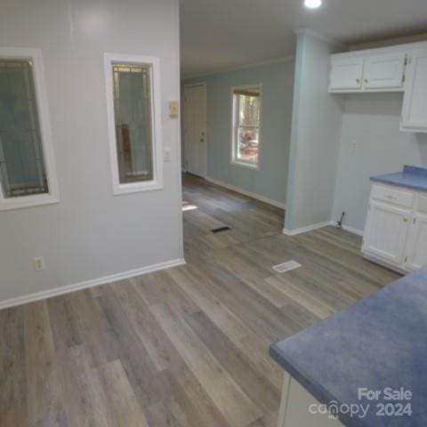 kitchen with white cabinets, light hardwood / wood-style floors, and crown molding