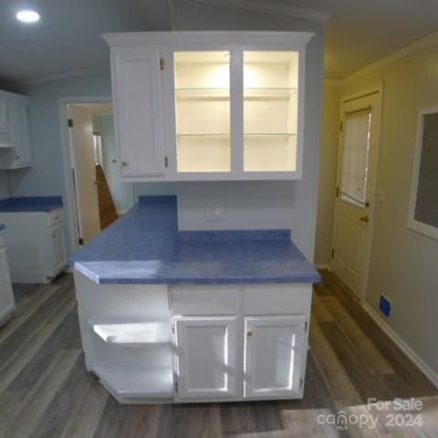 kitchen with crown molding, white cabinets, dark hardwood / wood-style floors, and lofted ceiling