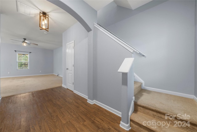 stairs featuring ceiling fan and hardwood / wood-style flooring