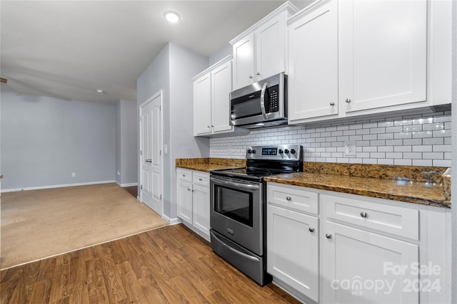 kitchen featuring decorative backsplash, stainless steel appliances, dark stone countertops, light hardwood / wood-style floors, and white cabinetry