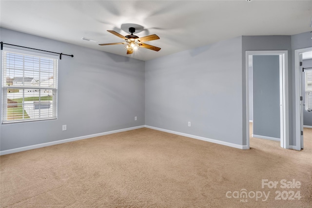 empty room featuring ceiling fan and light colored carpet