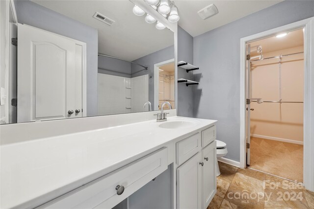 bathroom featuring tile patterned floors, walk in shower, vanity, and toilet