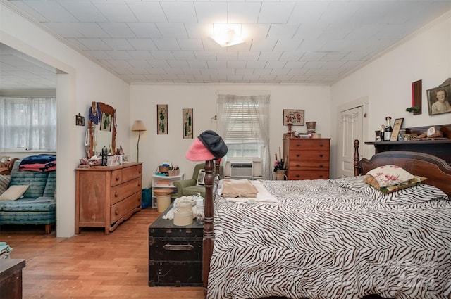 bedroom with cooling unit, ornamental molding, and light wood-type flooring