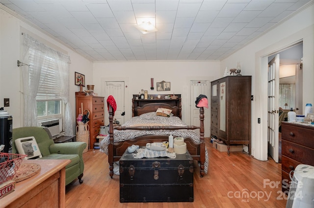 bedroom featuring crown molding, cooling unit, and light wood-type flooring