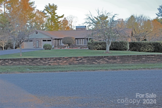 ranch-style home featuring a garage and a front lawn