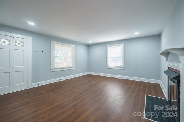 unfurnished living room with dark hardwood / wood-style floors and a healthy amount of sunlight