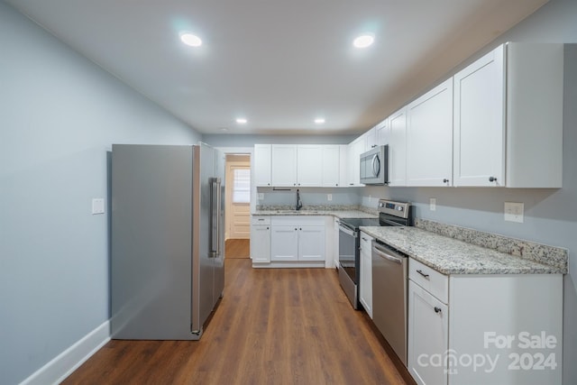 kitchen with light stone countertops, white cabinetry, sink, stainless steel appliances, and dark hardwood / wood-style floors