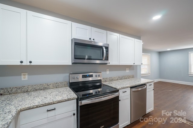 kitchen featuring light stone countertops, dark hardwood / wood-style flooring, white cabinetry, and stainless steel appliances