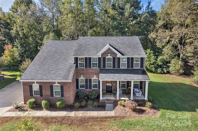 colonial-style house featuring covered porch and a front lawn