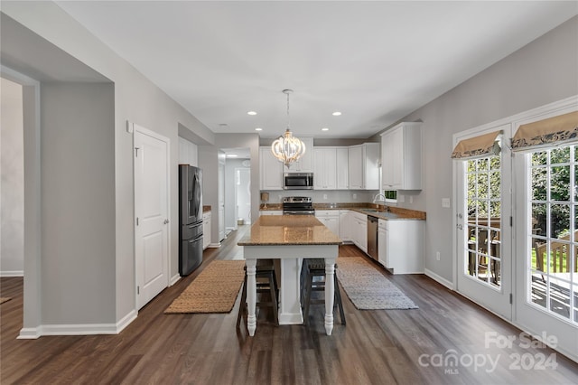 kitchen featuring white cabinetry, a center island, hanging light fixtures, and appliances with stainless steel finishes