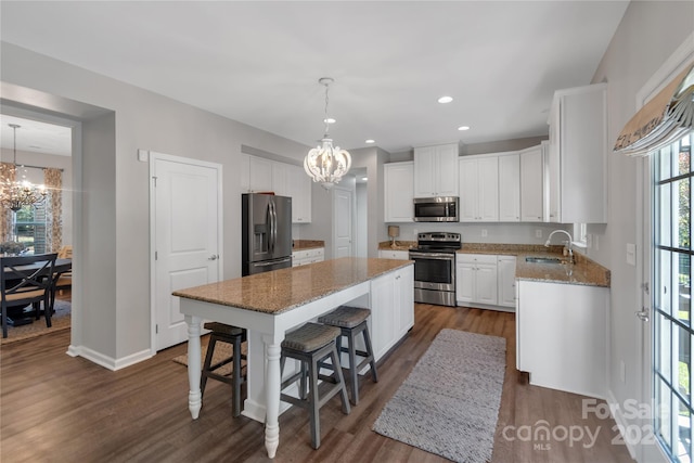 kitchen with dark wood-type flooring, white cabinets, sink, appliances with stainless steel finishes, and a kitchen island