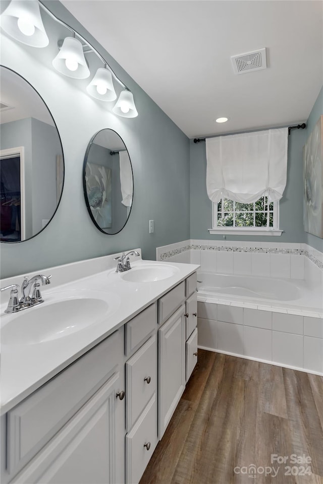 bathroom featuring tiled tub, hardwood / wood-style floors, and vanity