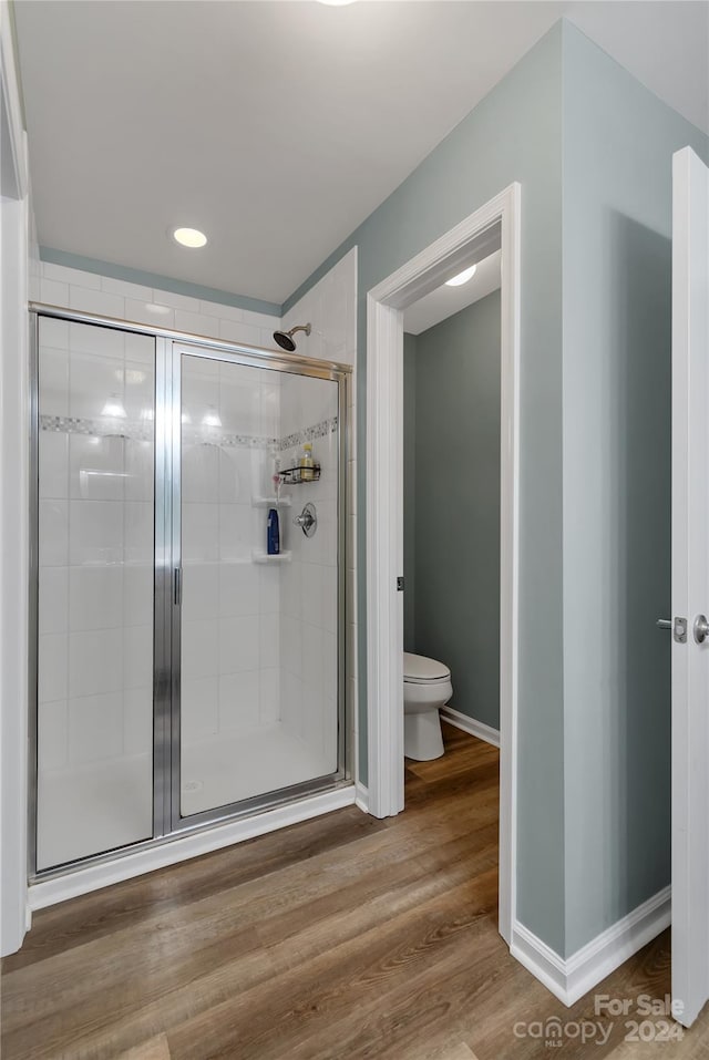 bathroom with hardwood / wood-style floors, toilet, and walk in shower