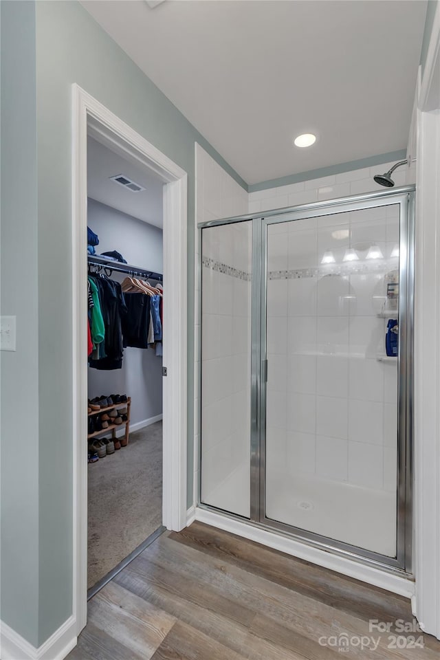 bathroom with hardwood / wood-style flooring and walk in shower