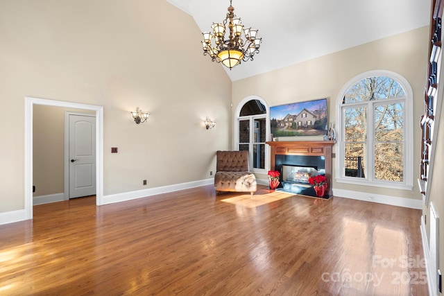 living area with high vaulted ceiling, a chandelier, and hardwood / wood-style flooring