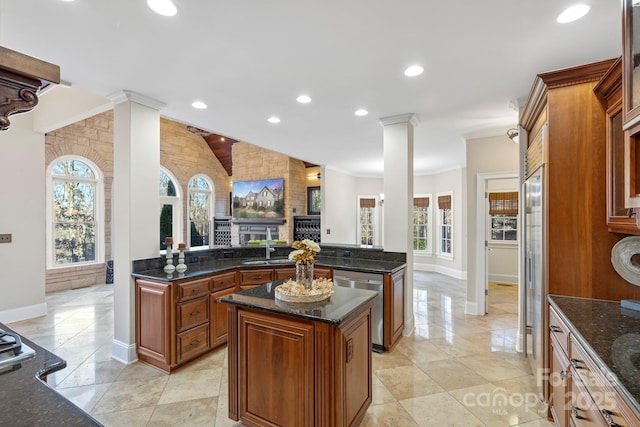 kitchen featuring a center island, crown molding, stainless steel appliances, and dark stone counters