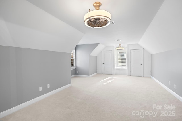 bonus room with light colored carpet and vaulted ceiling