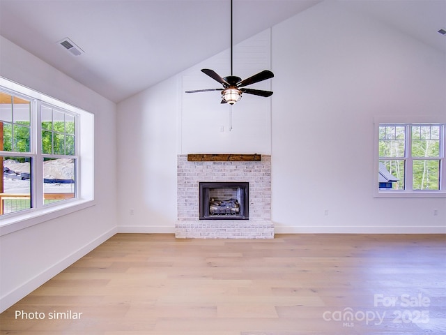 unfurnished living room featuring ceiling fan, high vaulted ceiling, light wood-type flooring, and a brick fireplace